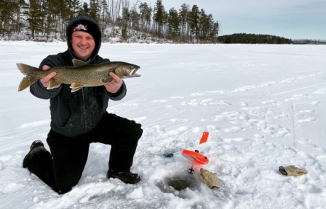 man holding trout on frozen lake